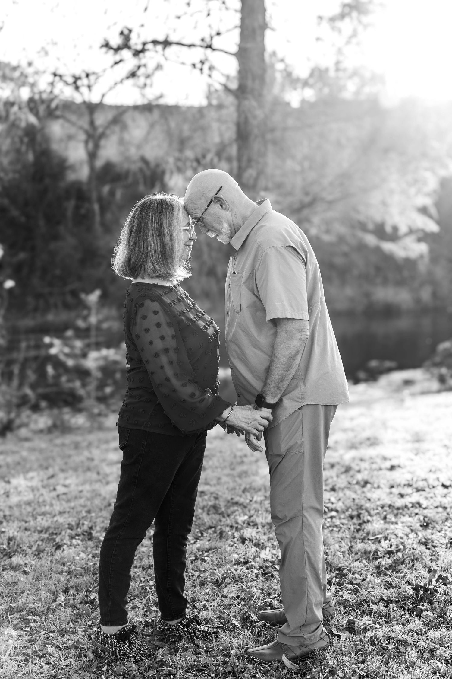 Black and white portrait of a romantic couple sharing an intimate moment outdoors.
