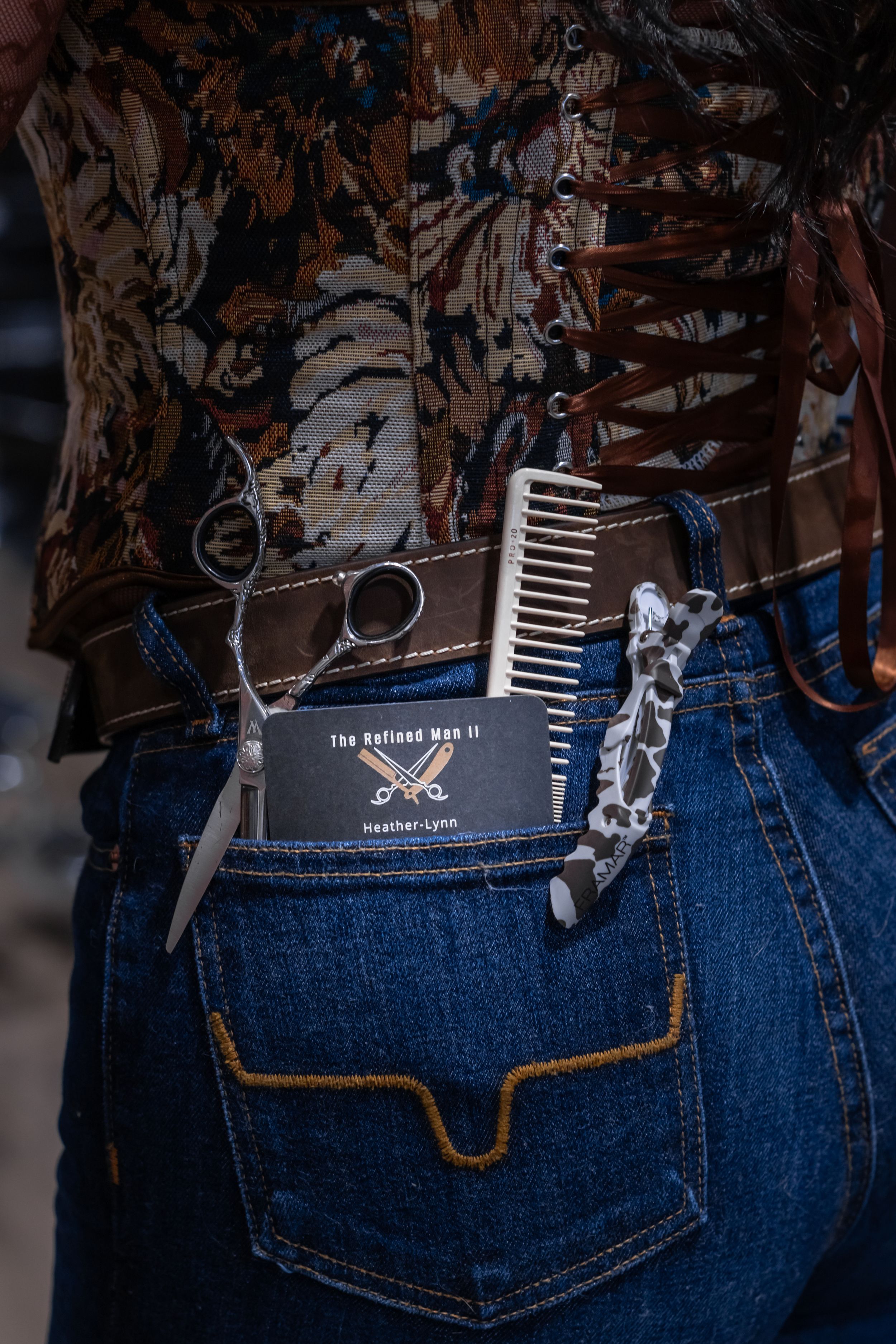 Female barber with tools and business card tucked in back jeans pocket at The Refined Man II.