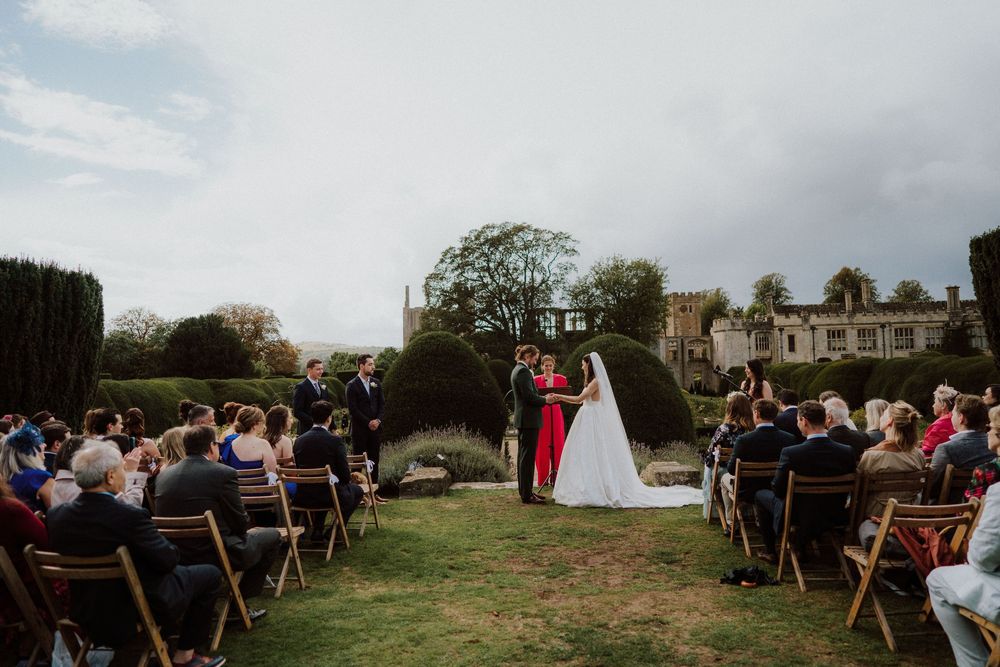 Wide angle view of an outdoor wedding ceremony with wooden chairs and natural landscape.