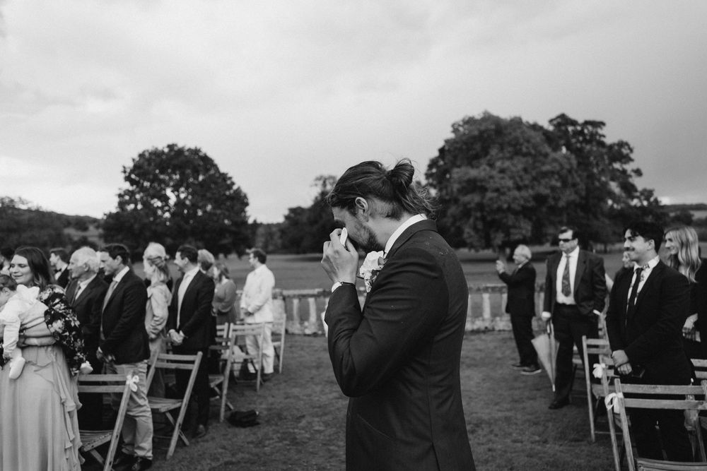 Black and white panorama of wedding guests seated at an outdoor ceremony.