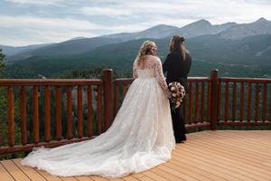 Couple's wedding ceremony on elevated deck with panoramic mountain landscape views.