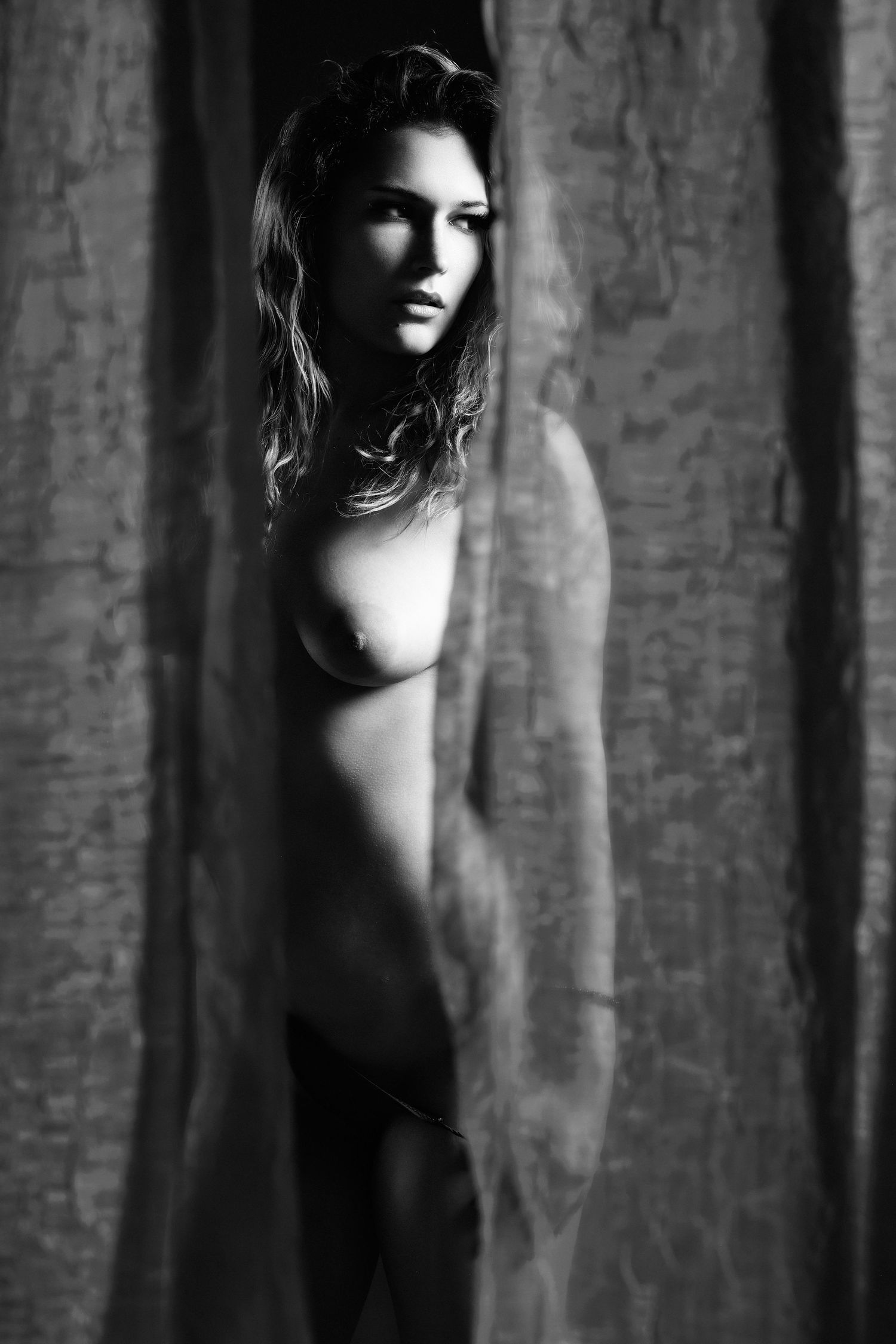 David G Holt Photography - Moody black and white portrait through textured curtains creating mysterious ambiance.