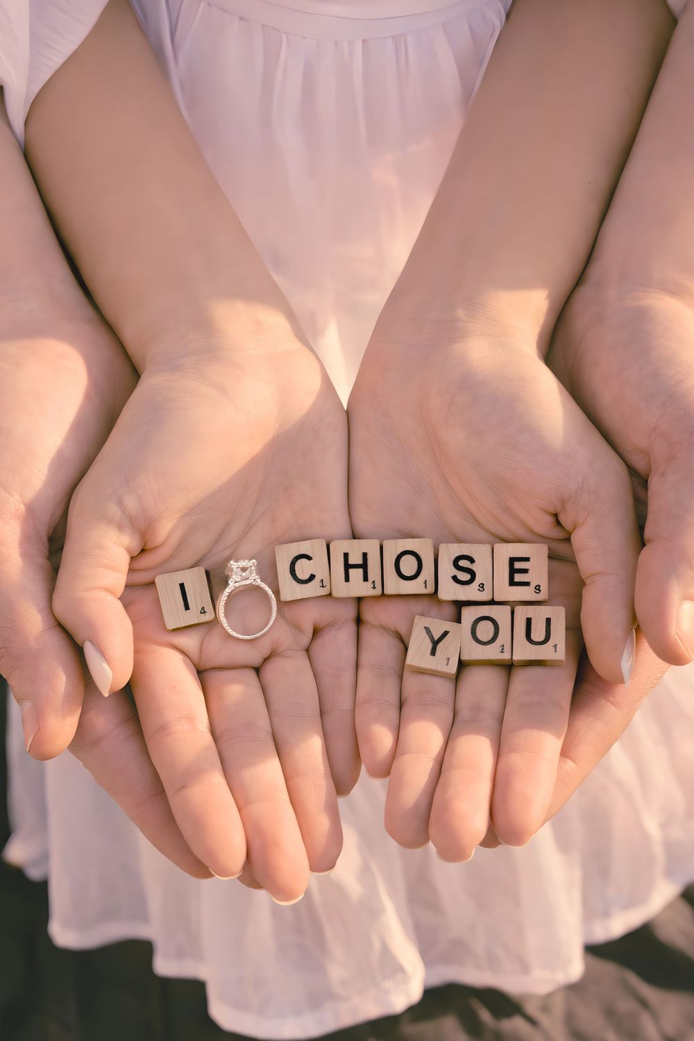 couple hands together holding letters spelling out a phrase of i chose you with ring