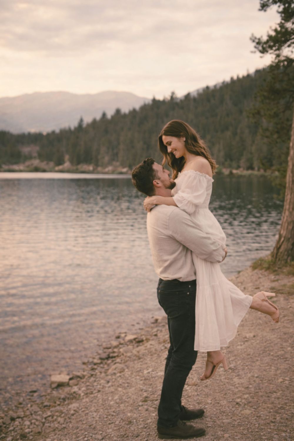 intimate moment of man holding woman near a lake