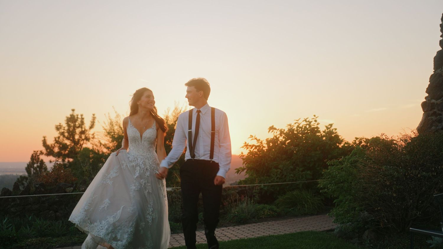 A joyful couple shares a laugh together in an outdoor garden setting during their wedding celebration.