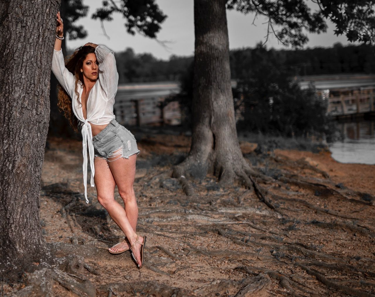 Outdoor lifestyle portrait of a woman posing by a tree near the water