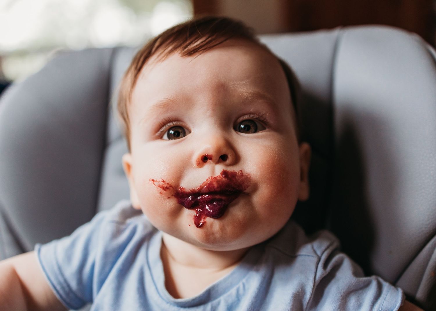 A collage of four close-up photos showing a baby's face with chocolate or food smeared around their mouth.