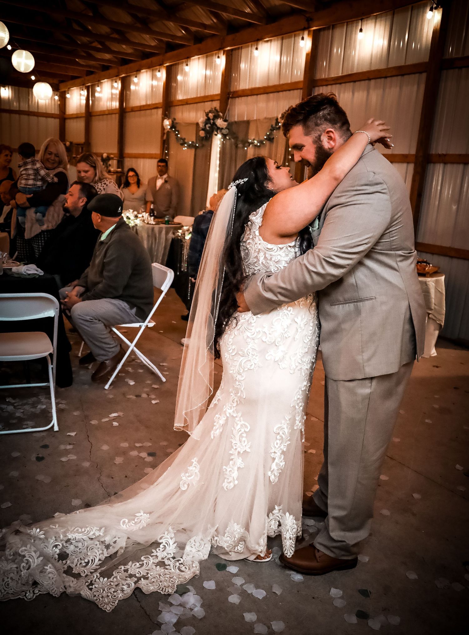 Wedding couple sharing their first dance in rustic barn venue with string lights.
