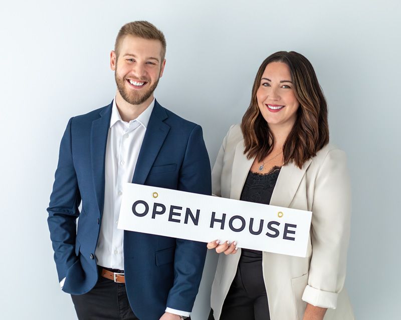 Real estate team holding an open house sign