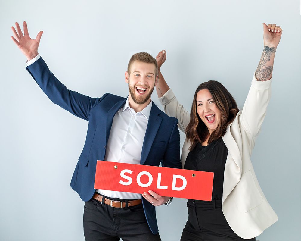 Real estate team from Chilliwack, celebrating with sold sign, successful property sale