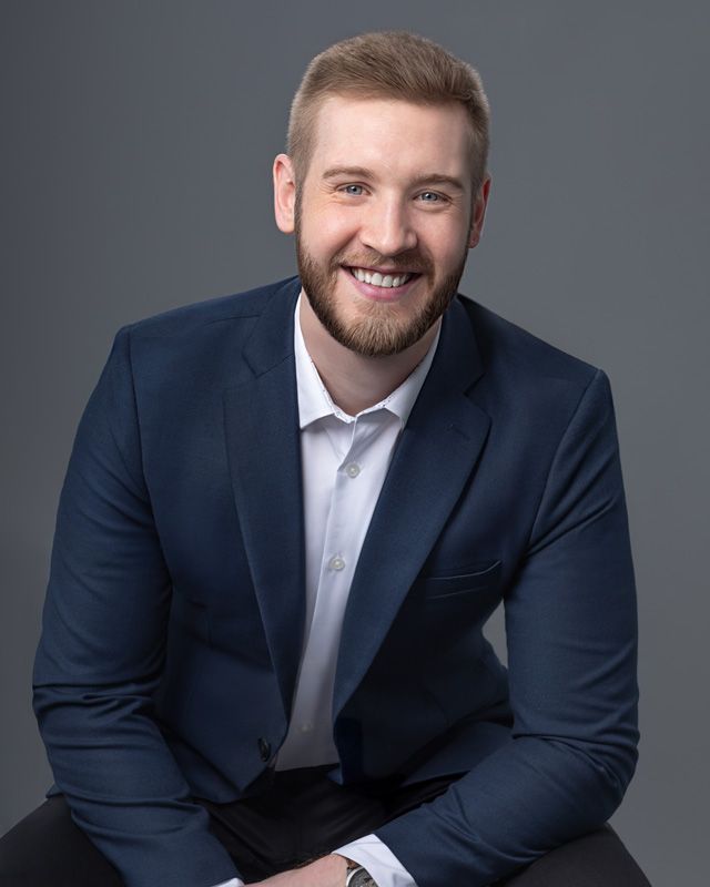 Corporate headshot of real estate team member, clean neutral background