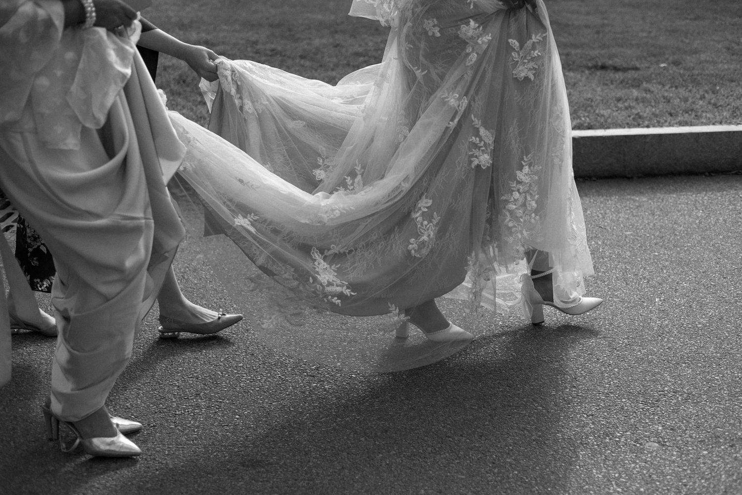 Black and white photo series showing the flowing movement of a wedding dress train being carried along a paved path.