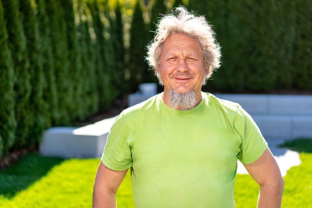 Person in bright green shirt smiling while exercising outdoors in sunny garden setting.