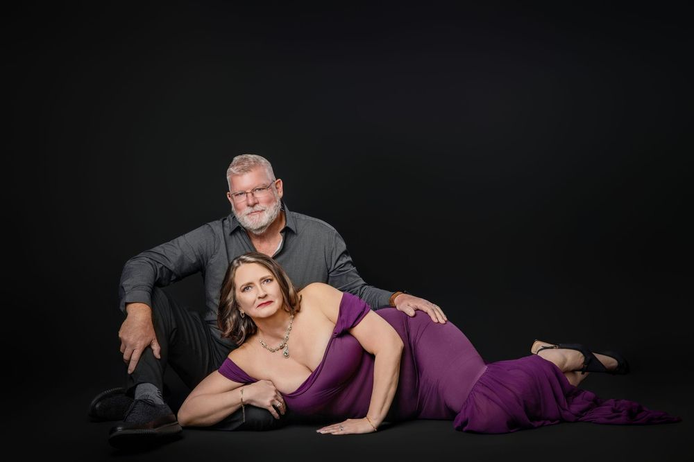Elegant couple in formal attire pose dramatically against dark background in studio portrait. Knoxville TN couple photography session.