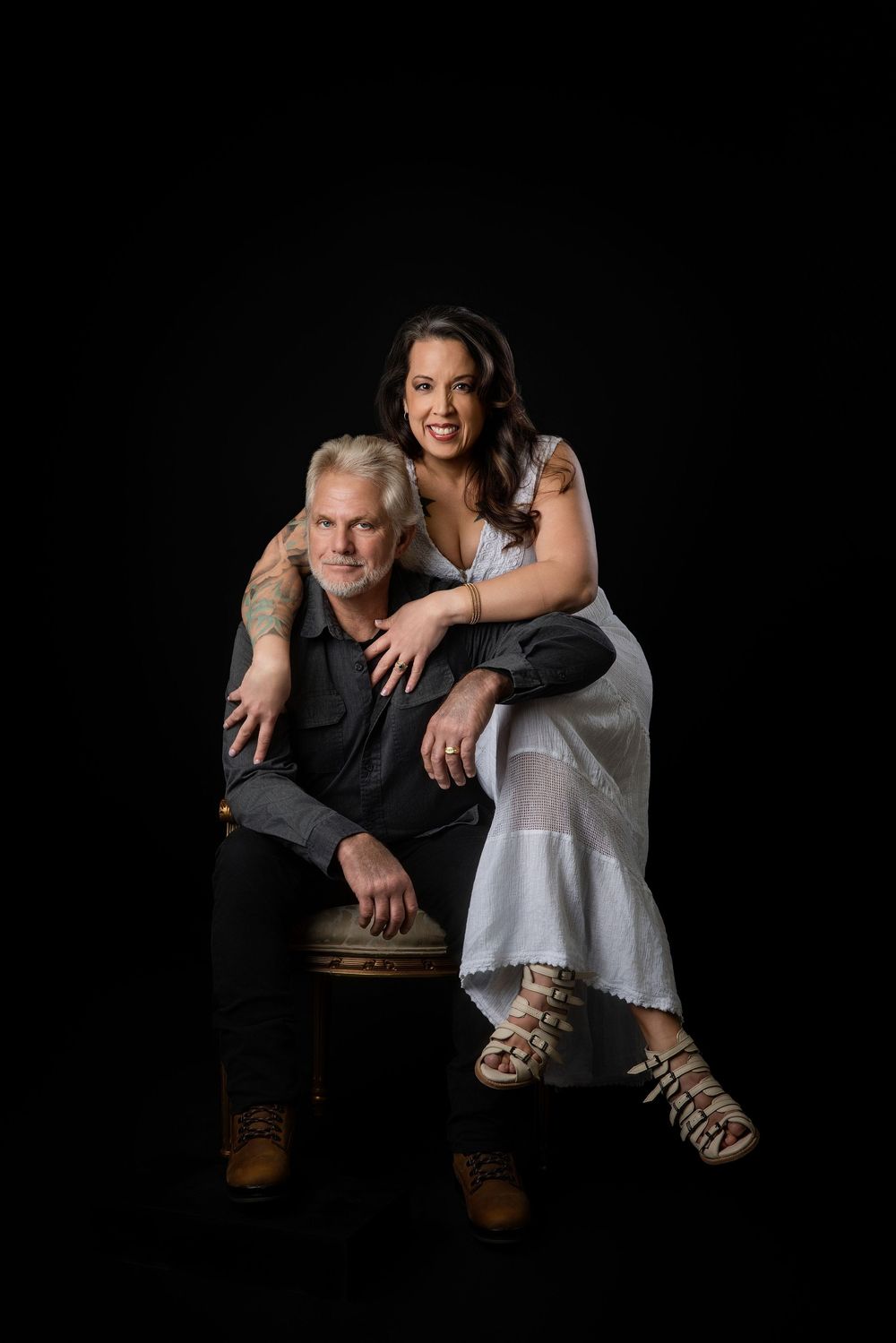 Studio portrait of two people posing together against black background in casual attire. Knoxville TN couple photography session.