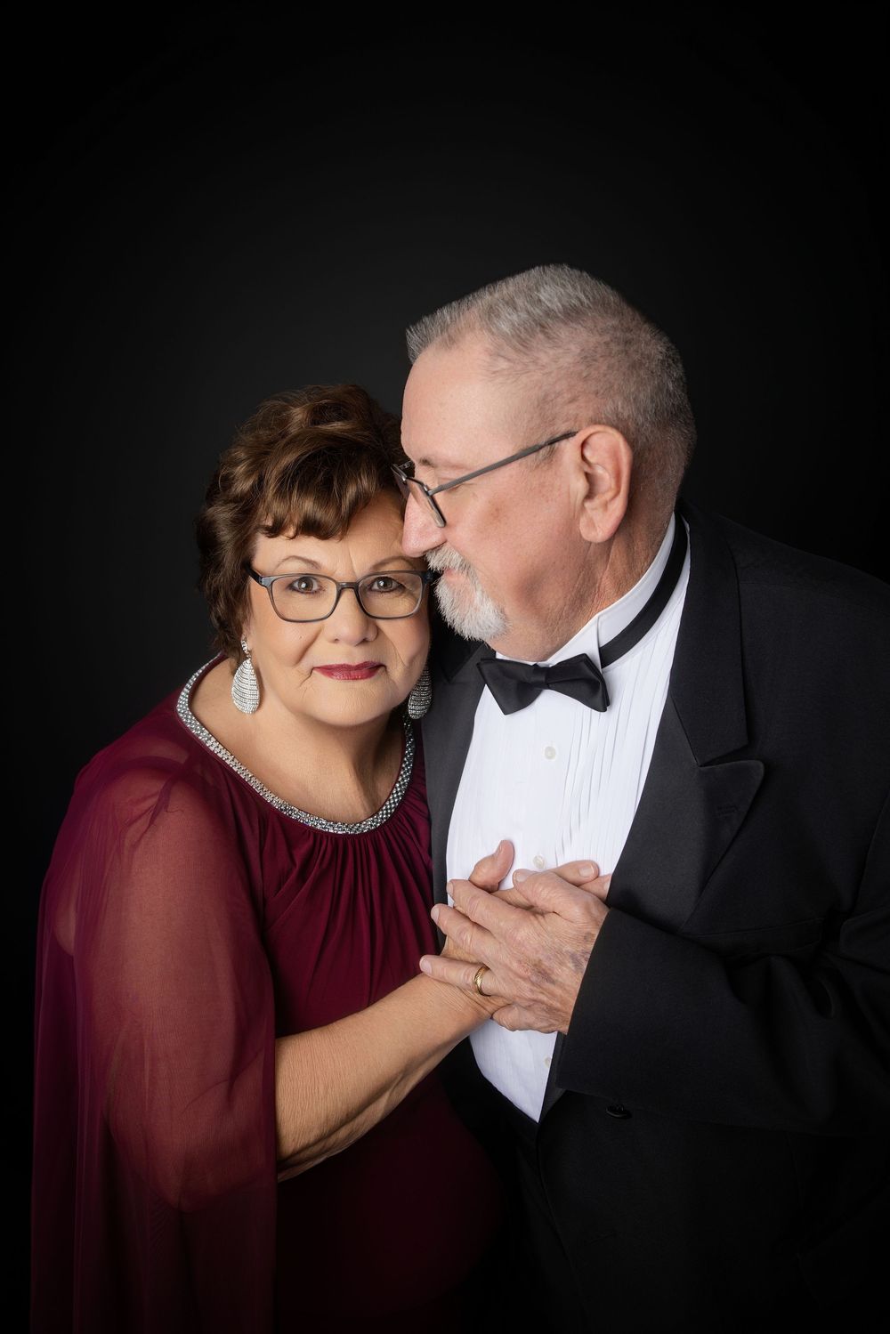 Romantic couple portrait series with burgundy dress and tuxedo against black background. Knoxville TN couple photography session.