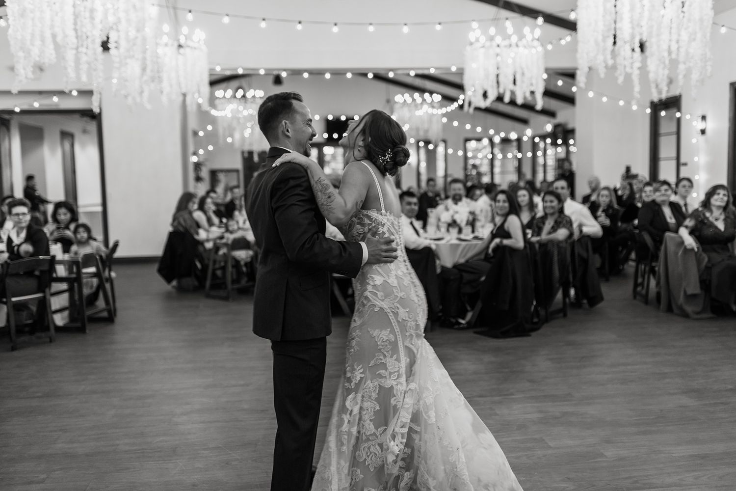 Couple shares their first dance at wedding reception while guests watch from tables in an indoor reception setting at San Clemente Shores.