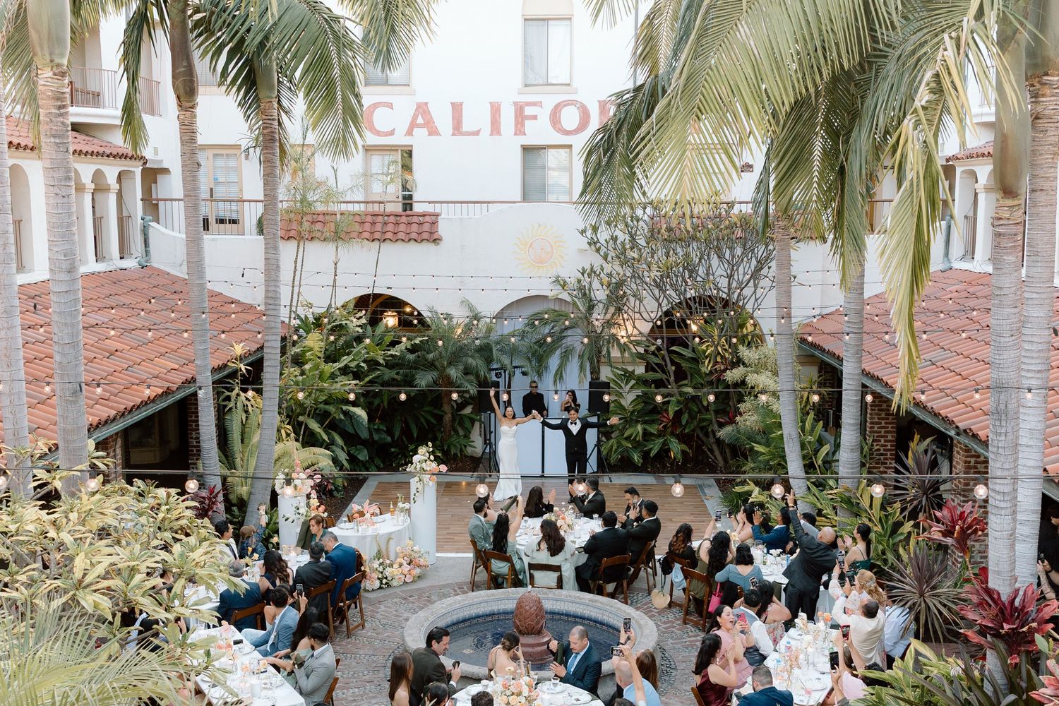 Outdoor wedding ceremony setup with palm trees, white chairs, and string lights creating a romantic tropical atmosphere.