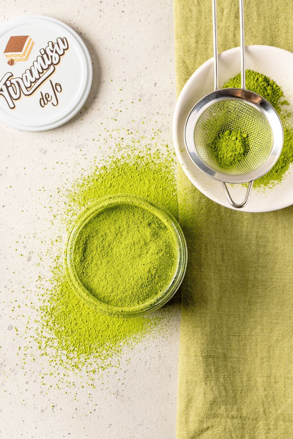Several small white bowls containing vibrant green matcha powder arranged on a light green textile surface.
