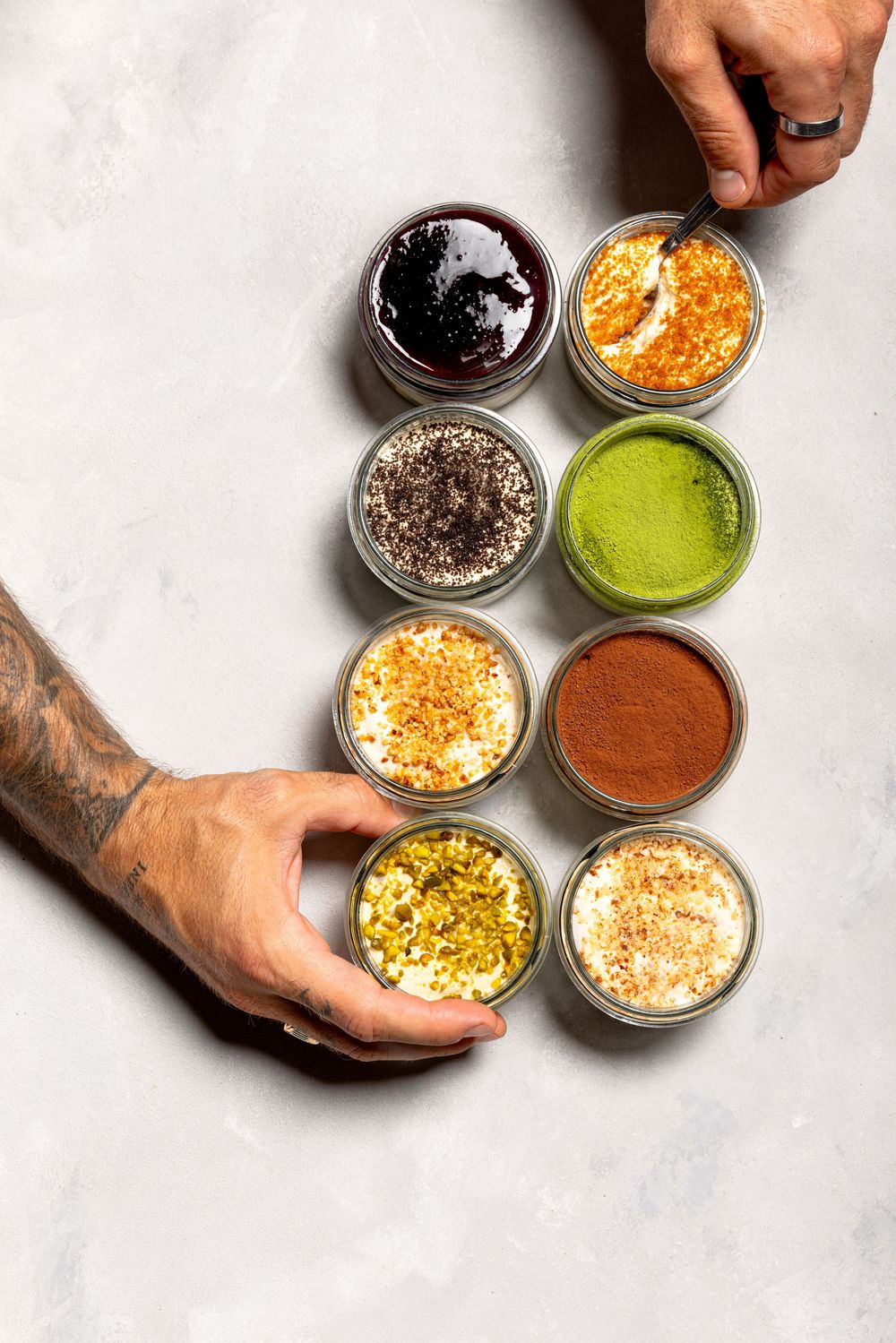 Various colorful sauces and toppings in small glass bowls arranged on a white surface.