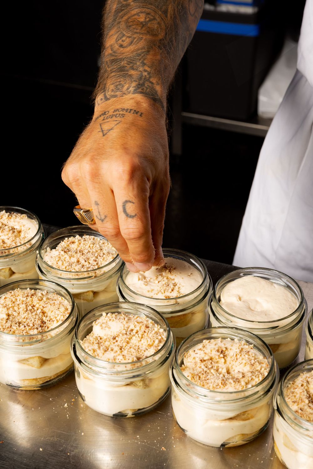 A sequence showing hands sprinkling toppings onto individual servings of creamy dessert in glass jars.