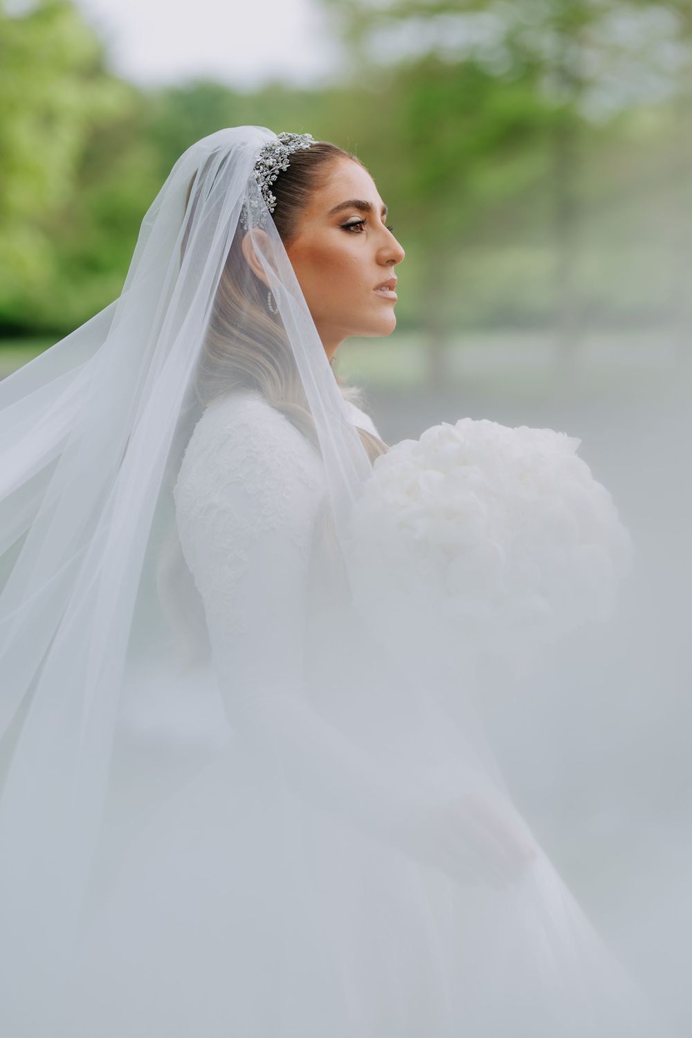 Ethereal bridal portrait with flowing veil against soft natural lighting.