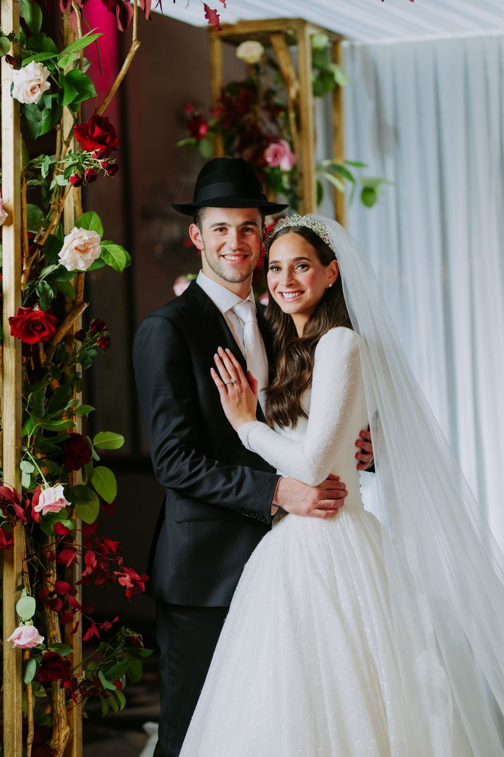 Wedding ceremony setting with floral decorations and white drapery.