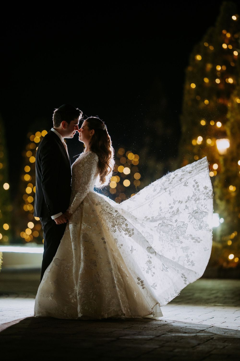 A romantic nighttime wedding photoshoot with twinkling lights creating a magical atmosphere.
