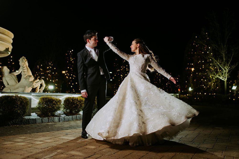Silhouettes dance under twinkling lights at an evening wedding celebration.