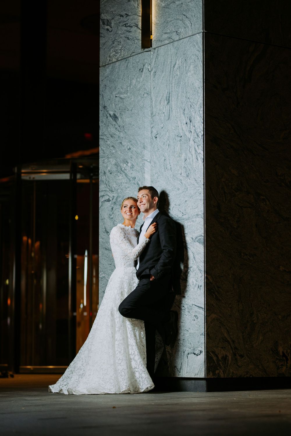 Dramatic low-light wedding portrait against marble columns.