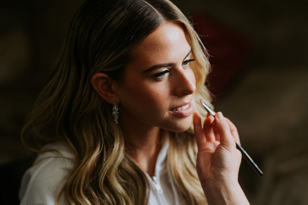 Intimate bridal preparation moment captured in warm, moody lighting.