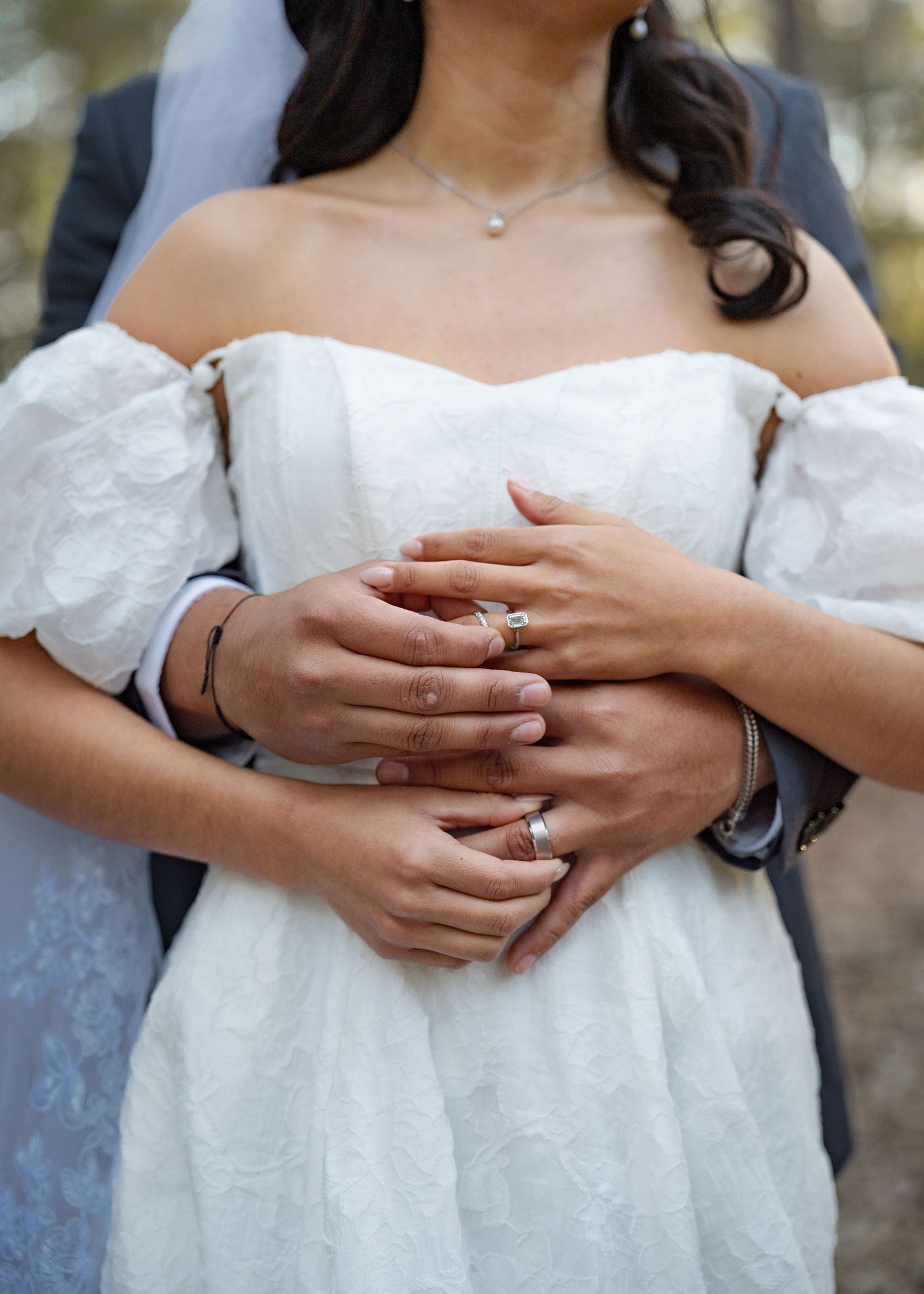 Close-up of couple’s hands and wedding rings among leaves during forest elopement in Texas woods