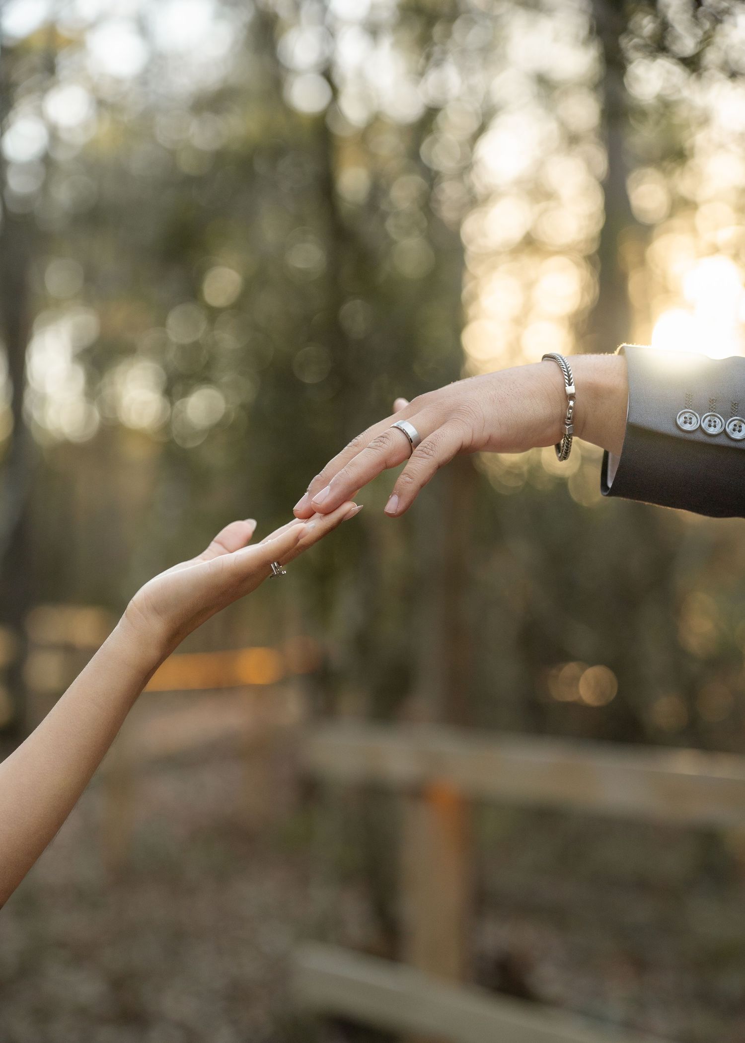 Close-up of couple’s hands and wedding rings among leaves during forest elopement in Texas woods