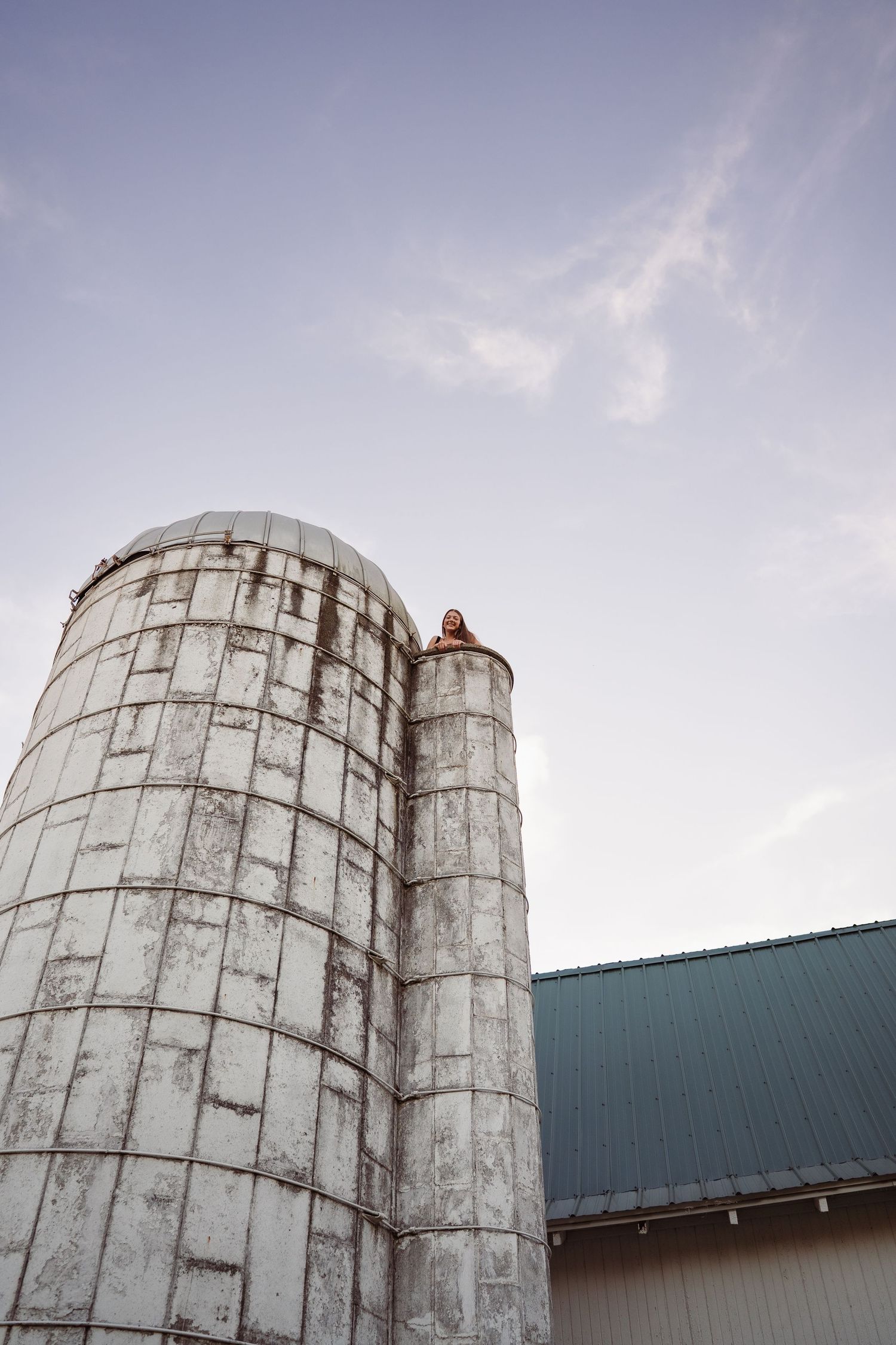 White industrial silos against sunset sky with person visible at top.