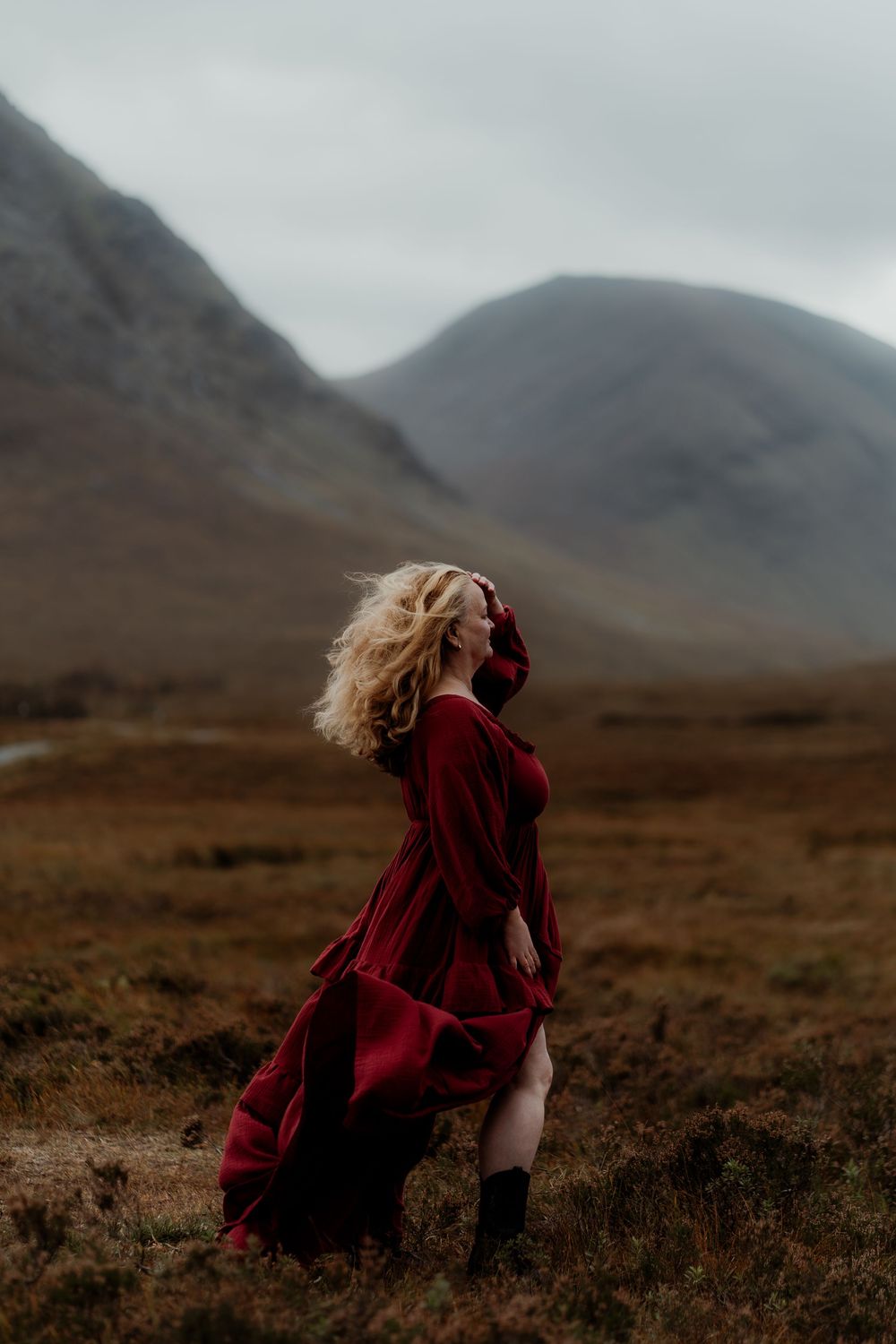 Dramatic sequence of a person in a flowing red dress walking across a misty Scottish Highland landscape with mountains.