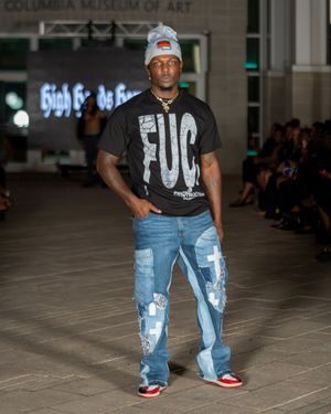 Fashion model walks runway wearing distressed denim jeans and black graphic t-shirt at Columbia Museum of Art show.