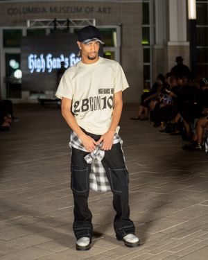Casual streetwear look with graphic tee and black cargo pants shown at museum fashion event.