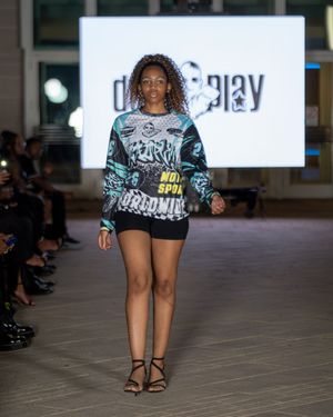 Model struts down catwalk wearing graphic print t-shirt and shorts combination.