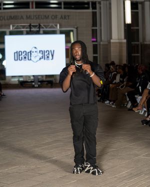 Designer in all-black ensemble presents collection at Columbia Museum fashion show.