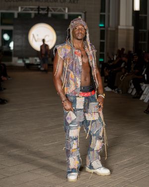 Model presents distressed denim patchwork outfit on fashion runway.