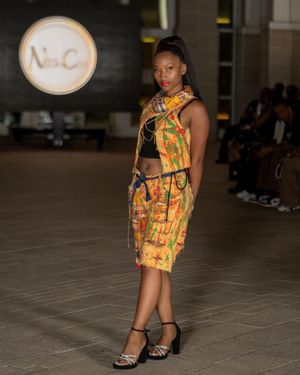 Model presents vibrant yellow and orange patterned outfit on museum runway.