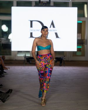 Runway show featuring vibrant multicolored pants and tops with artistic prints.
