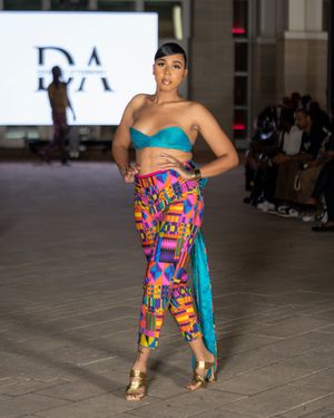 Colorful geometric print outfit with turquoise accent shown on museum runway.