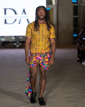 Fashion models showcase yellow and multicolored shorts designs on the catwalk.