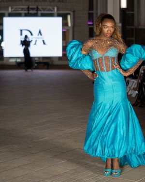 Turquoise tulle gown with sheer bodice details glides down museum runway.