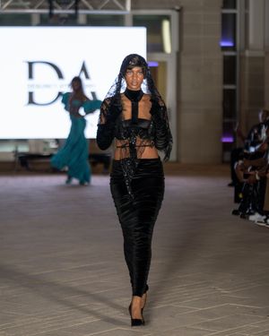 Sleek black evening wear ensemble presented on museum runway stage.