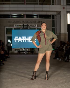 Model showcases olive green shorts and heels on runway at Columbia Museum of Art.