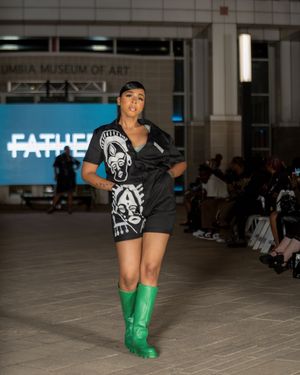Fashion model wearing black shorts and bright green knee-high boots struts down catwalk.