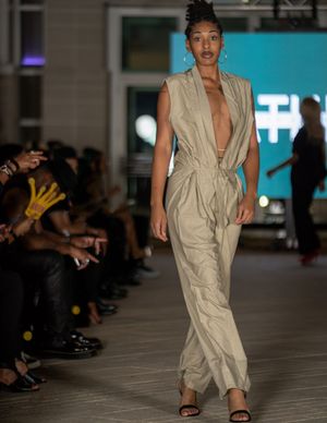 Model walks runway in beige utility jumpsuit at Columbia Museum fashion event.