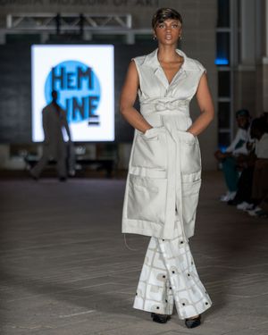 Model presents white utility-inspired ensemble with wide-leg pants during runway show.